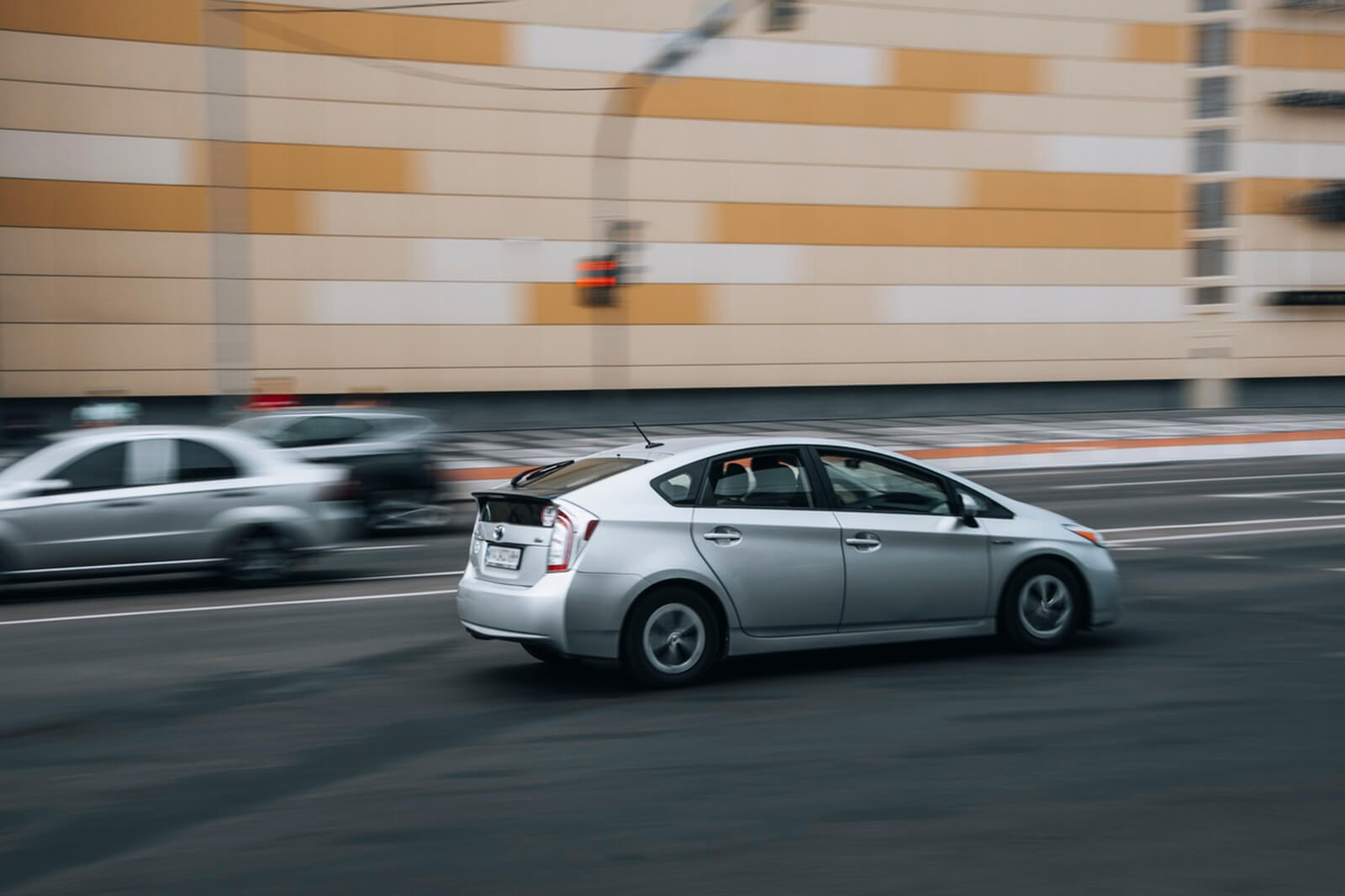 A silver Toyota Prius speeding on a public road.