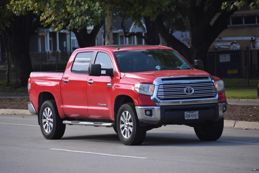 Red Toyota Tundra pickup truck driving down the street after hitting one million miles.