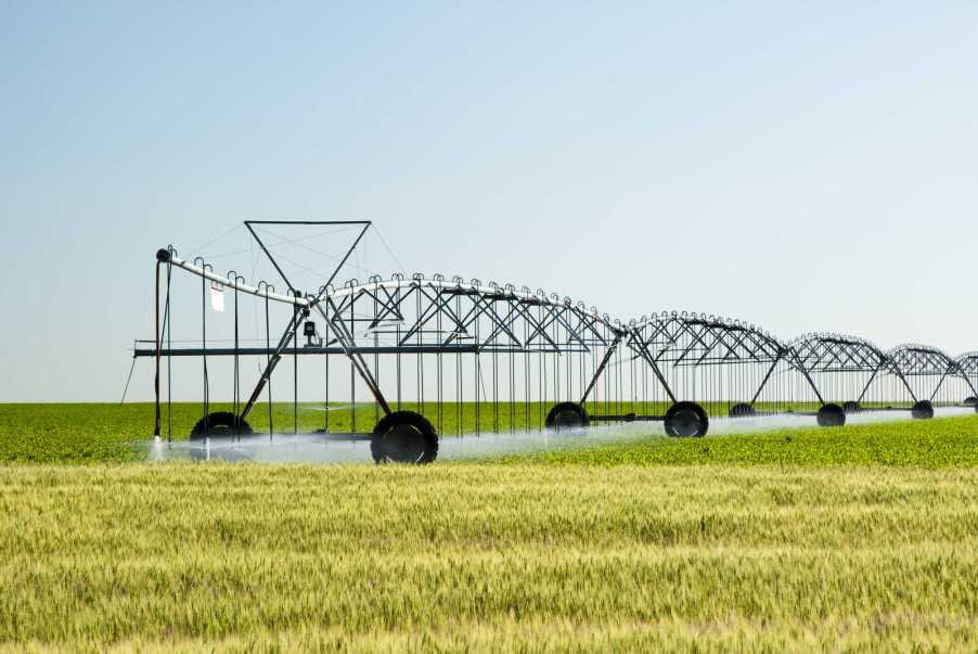A center pivot irrigation system spraying a large green field