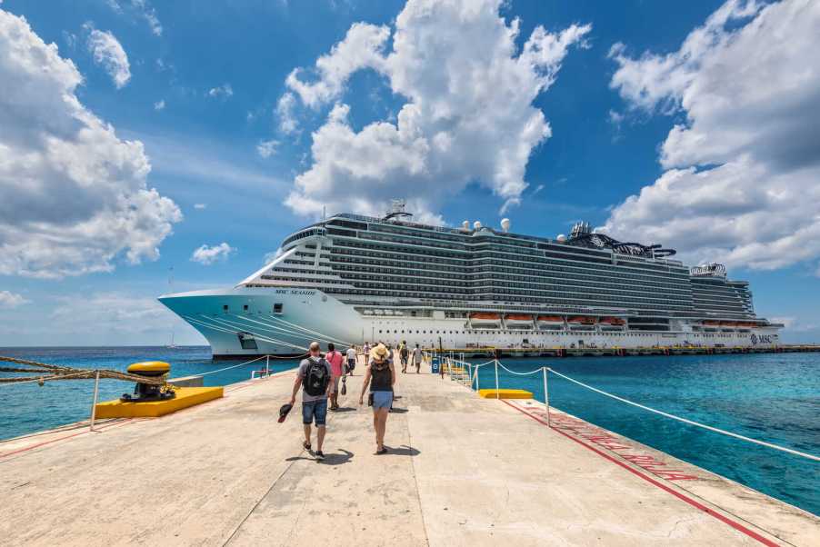 Cruise ship docked in Mexico with passengers walking on deck toward it
