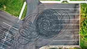 A drone's eye view of a parking lot covered in burnt rubber after a car did donuts
