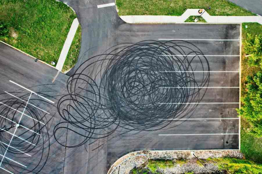 A drone's eye view of a parking lot covered in burnt rubber after a car did donuts