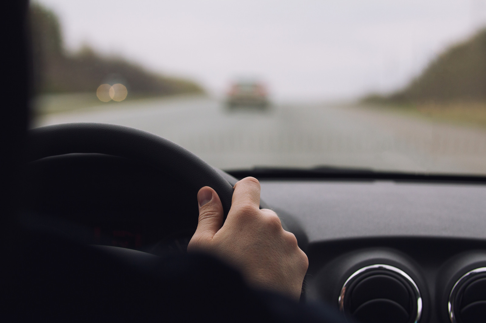 Hands driving a steering wheel inside car in close view
