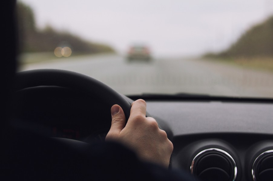 Hands driving a steering wheel inside car in close view