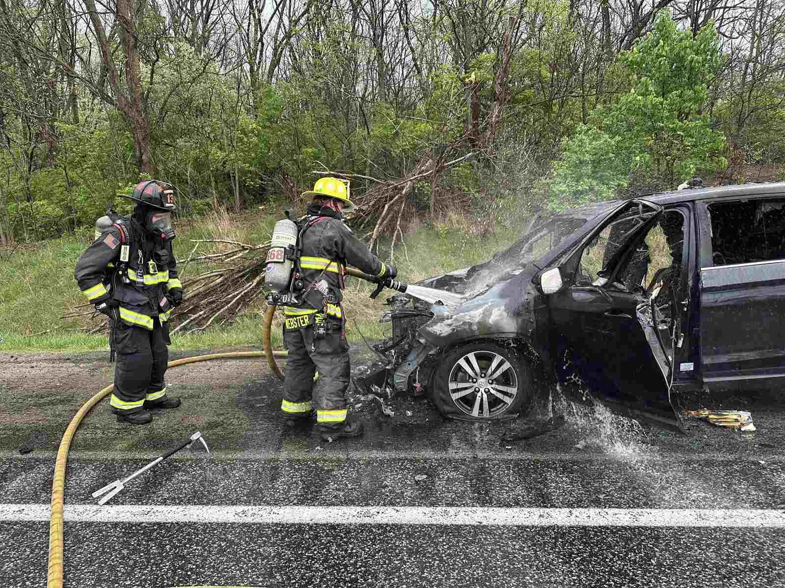Firefighters douse a Honda SUV that caught fire after a lightning stike