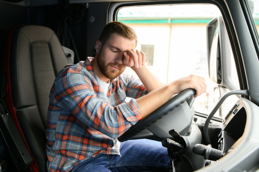 A trucker, looking upset in his semi-truck