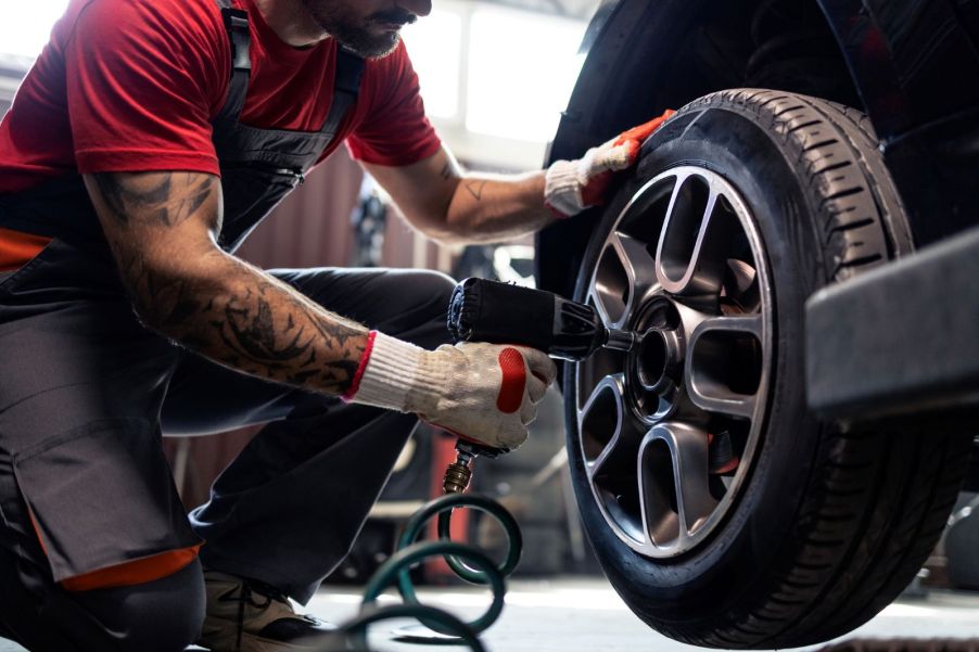 A mechanic using a pneumatic tool to tighten lug nuts on a customer car