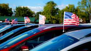 A row of new cars in close view of roofs with tiny American flags on each