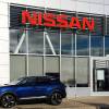 A Nissan Rogue parked in front of a Nissan dealership