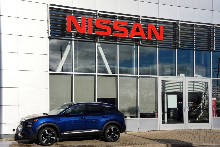 A Nissan Rogue parked in front of a Nissan dealership