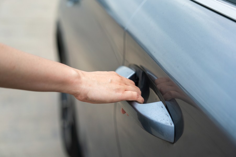 Hand and arm opening a car door in close view
