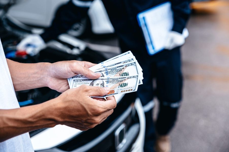 Man's hands paying a mechanic in $100 bills in close view