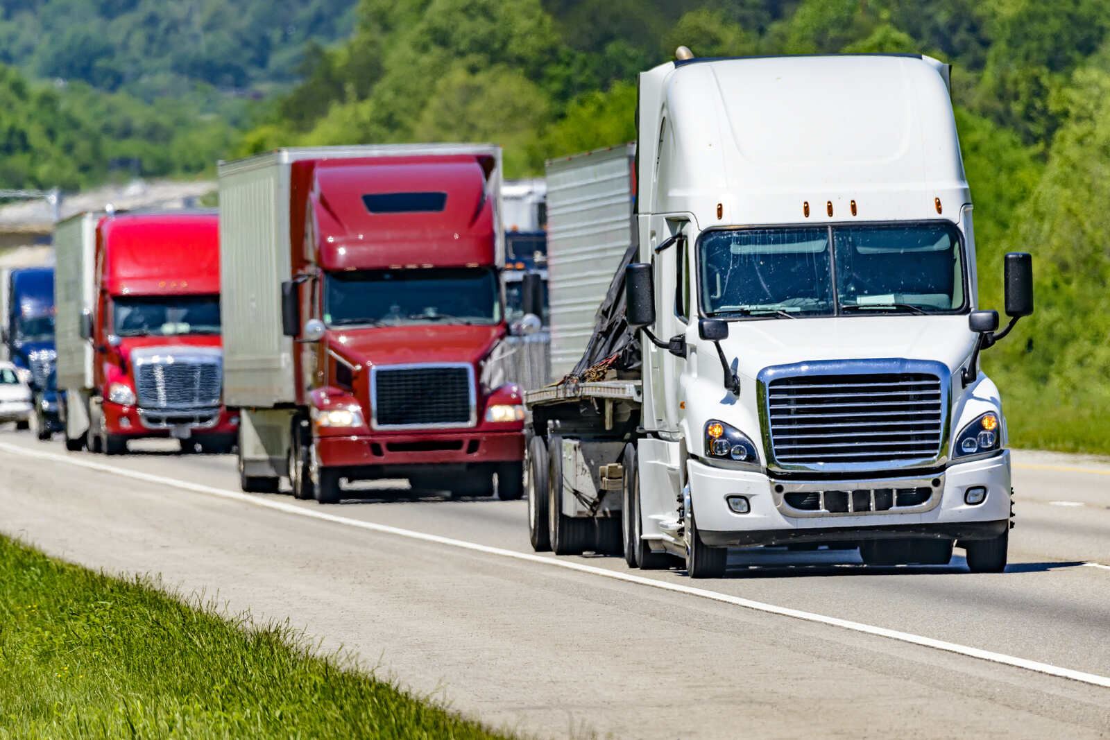 Several semi-trucks drive down a U.S. highway
