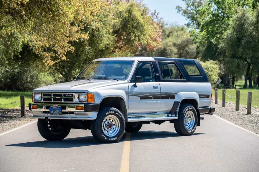 A light metallic 1986 Toyota 4Runner 22R-E parked in the middle of a two-lane road in left front angled view