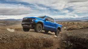 A blue 2024 Chevrolet Silverado ZR2 pickup truck parked on an incline in a rocky desert landscape