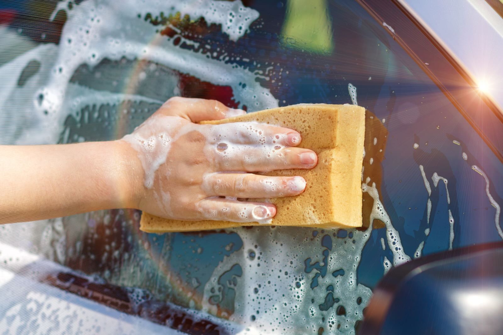 Dealership employee uses a sponge to handwash a car after a negotiation.
