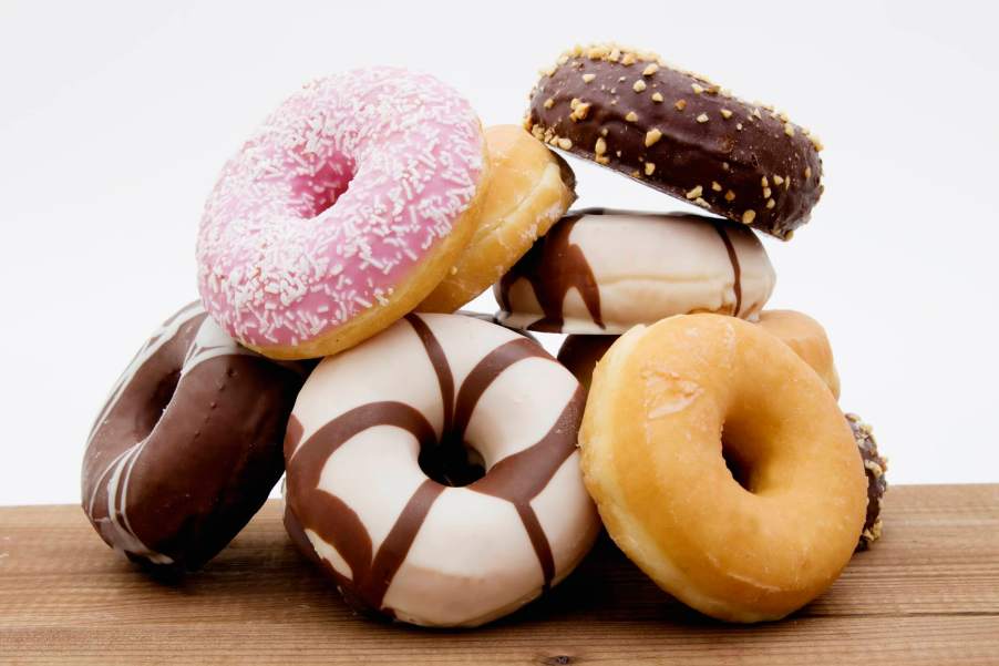 Stack of various donuts on a countertop, in front of a white background