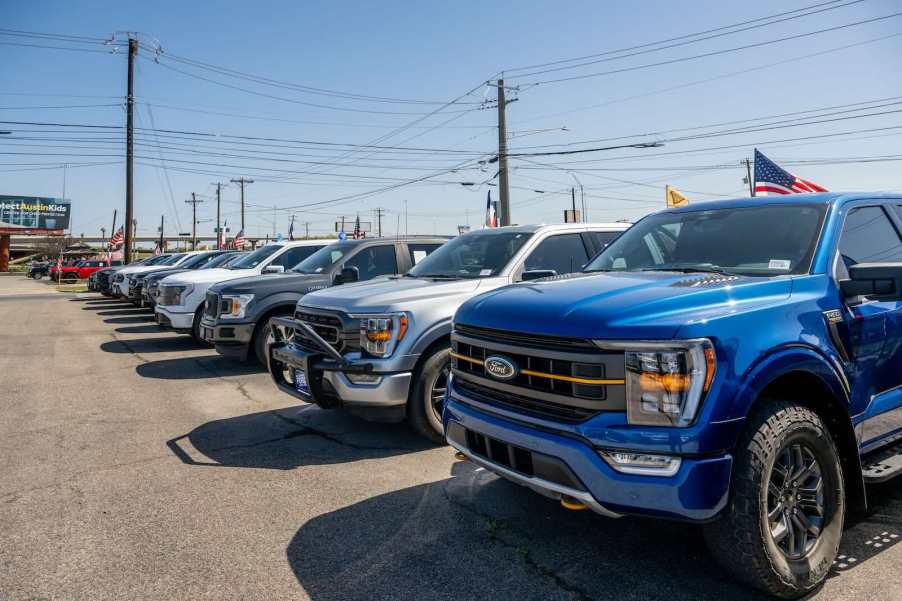 Row of recalled Ford F-150 pickup trucks at a dealership.
