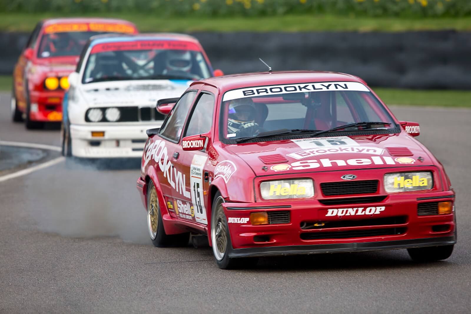 A red Ford Sierra Cosworth RS500 tackles a corner during a touring car race.