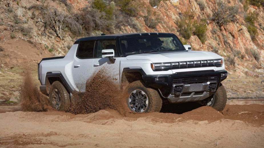 A GMC HUMMER EV kicks up dirt off-road.