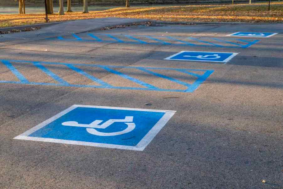 Two blue and white handicapped parking spaces in a lot, with trees visible in the background