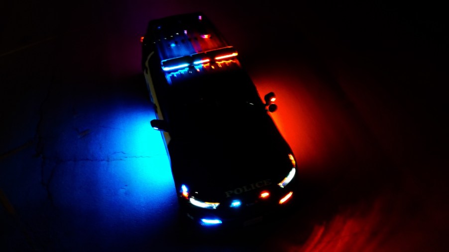 Police cruiser surrounded by blue and red lights.