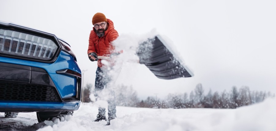 Man shovels snow out of his parking spot.