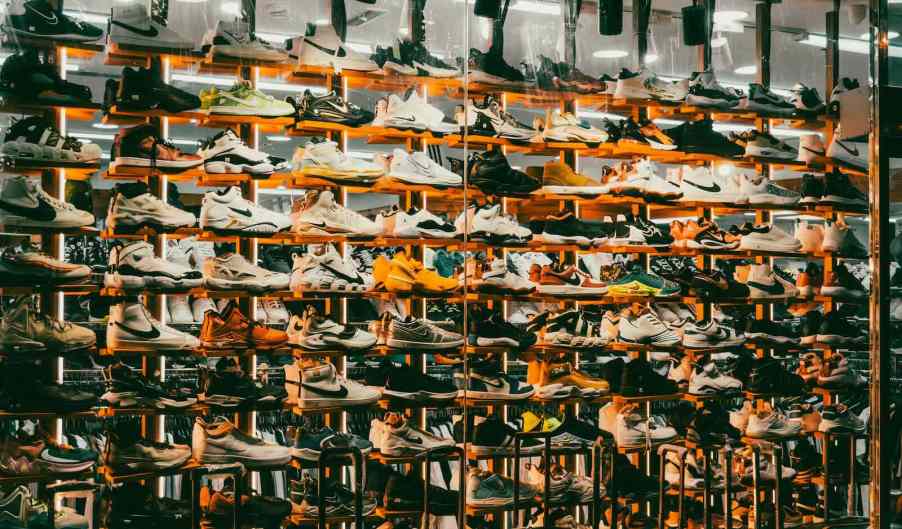 Shelves of Nike sneakers in front of a mirror in a store.