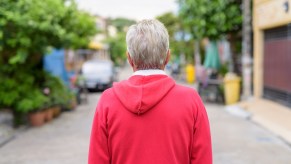 Suburban dad in red sweatshirt, watches street.