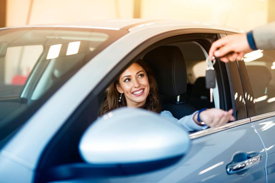 A smiling woman about to take a test drive at a dealership.