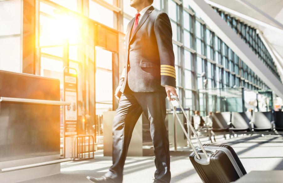 Commercial airline pilot walking in airport terminal with roller bag