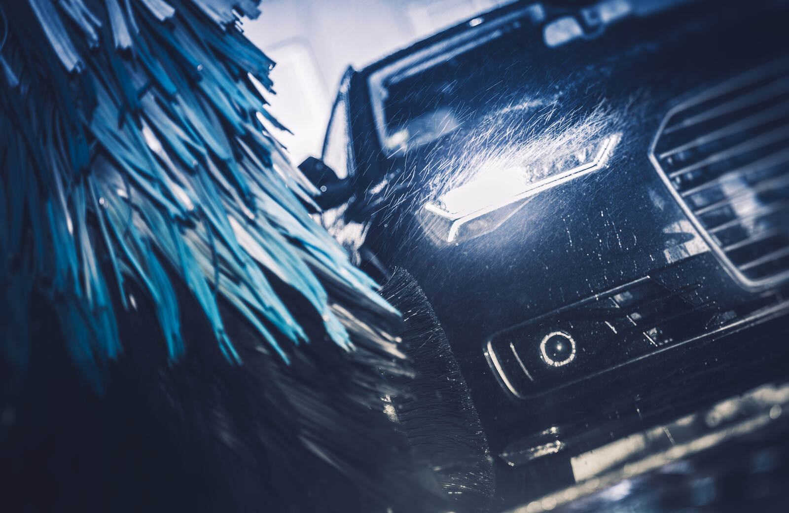 An automatic car wash in close view while brushes wash the front right side of a black vehicle