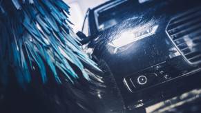 An automatic car wash in close view while brushes wash the front right side of a black vehicle