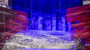 Car wash in action in close view of brushes and soap on car roof