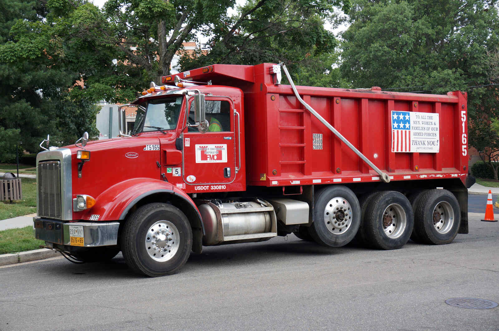 A red dump truck parked in left profile view