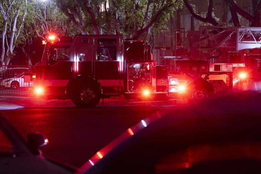 A fire truck at night parked in left profile view with lights on