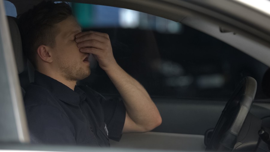 A police officer yawning in his car