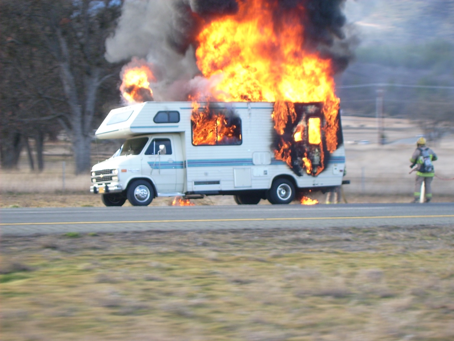 an RV on fire on the side of the road
