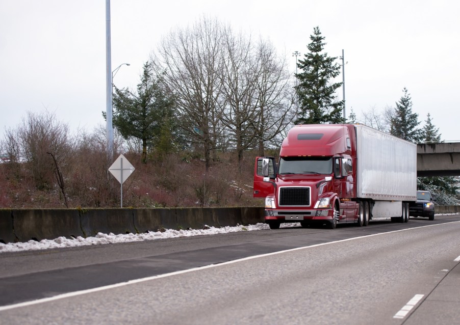 A semi-truck with a police car behind it