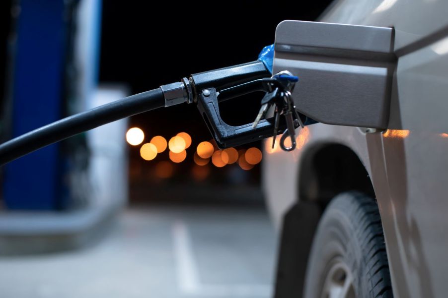 A gas station pump inside a car's fuel neck at night