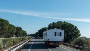 A double wide mobile home traveling down a highway