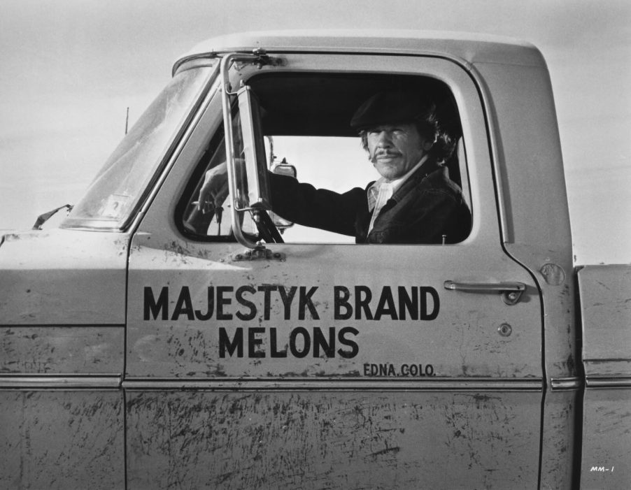 Actor Charles Bronson sits in the cab of a 1968 Ford F100 that says Mr. Majestyk on the door for a publicity photo