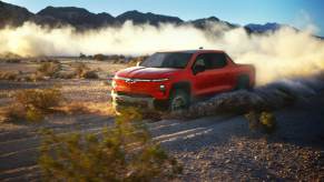 A 2026 Chevrolet Silverado EV Trail Boss driving on a dusty, rocky desert road. GM continues to invest more in ICE engines than EVs