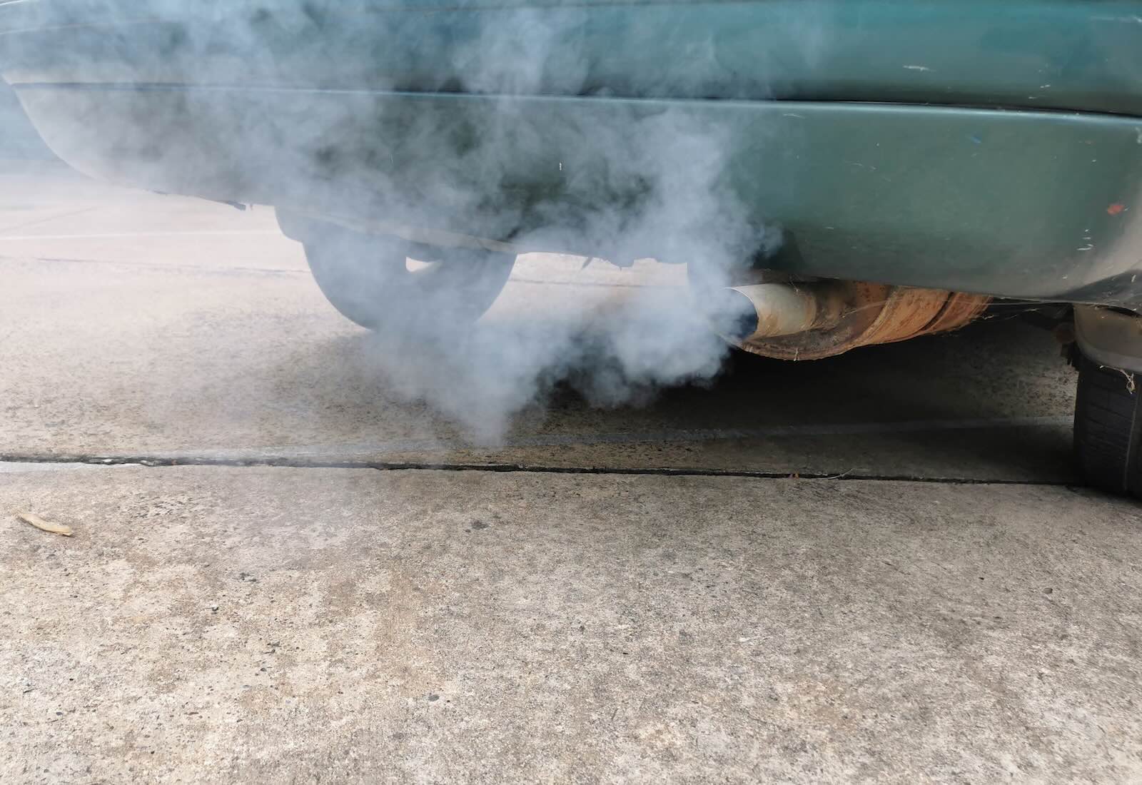 White smoke coming out of a car's tailpipe during Massachusetts annual emissions inspection.