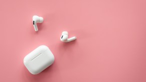 White Apple AirPods and case on a pink background.