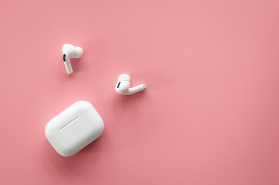 White Apple AirPods and case on a pink background.