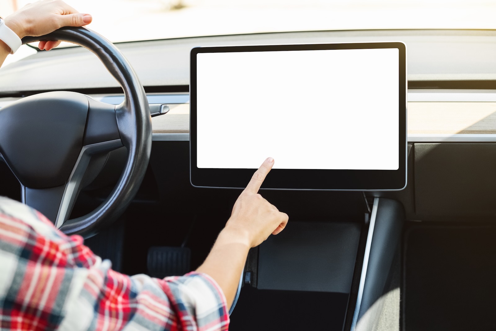 Woman taps a blank, white infotainment screen like those recalled in Cadillac Lyriq and Lincoln Nautilus crossover SUVs