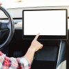 Woman taps a blank, white infotainment screen like those recalled in Cadillac Lyriq and Lincoln Nautilus crossover SUVs