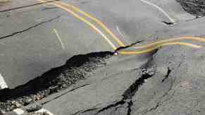 Road's asphalt surface buckles and breaks during heat wave.