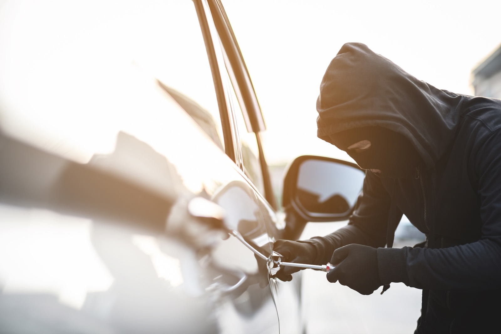 Masked thief opens the door lock on a G Wagon at the George Foreman estate